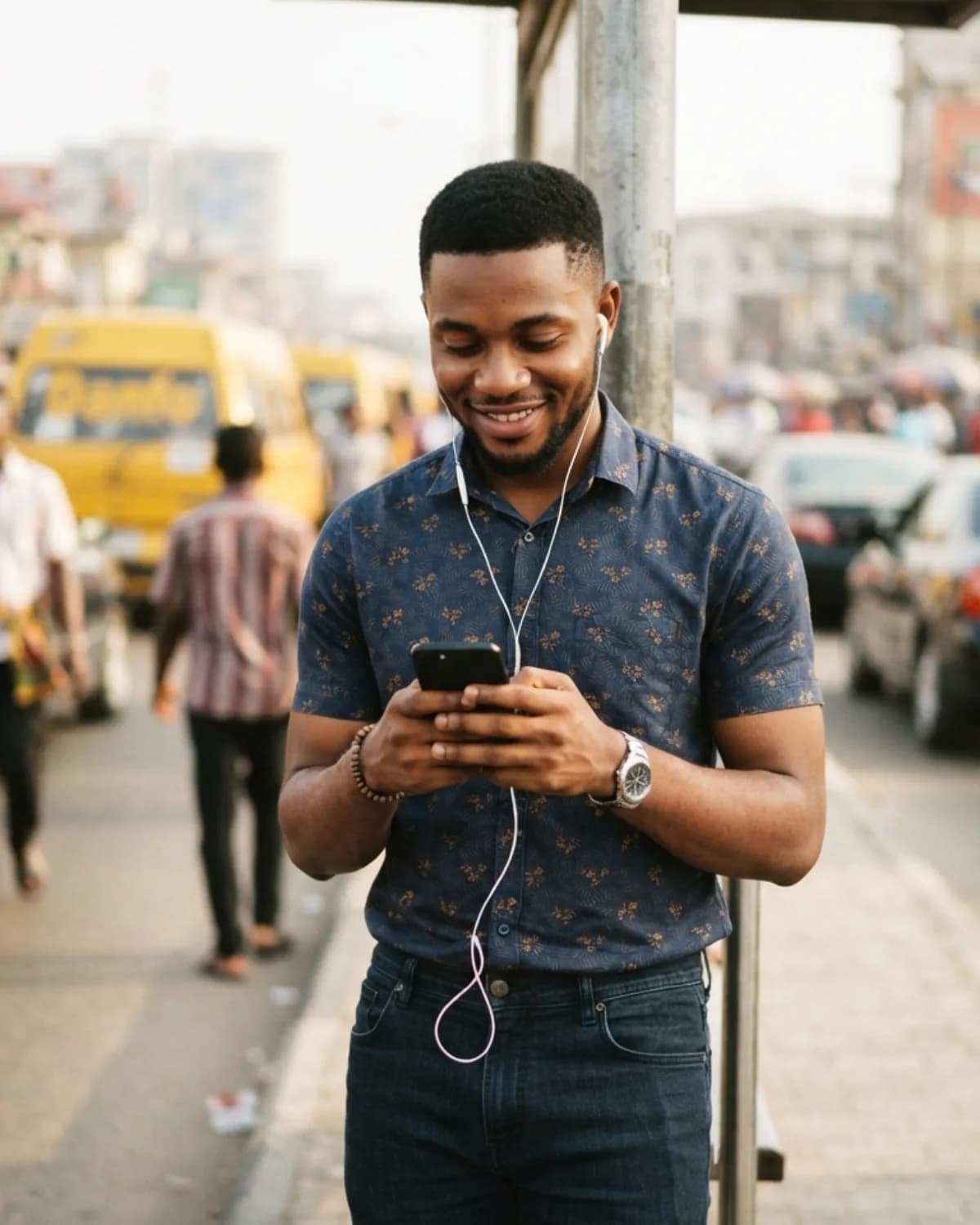 A young man at a bus stop, looking at his phone